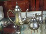 une théière en argent et une autre théière en argent posées sur une étagère en verre