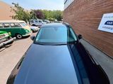 une voiture noire garée devant un immeuble sur lequel est accrochée une pancarte