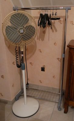 un ventilateur posé sur un pied dans une pièce
