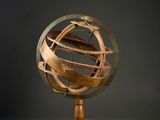 a wooden and metal globe on a stand with a black background