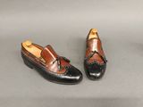 une paire de chaussures noires et marron posées sur une surface grise