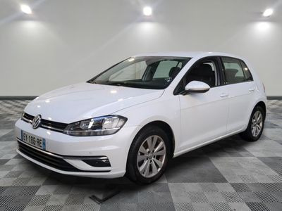 Une Volkswagen Golf blanche est garée dans une pièce dont le sol est en damier.