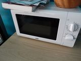 a microwave sitting on top of a table next to a basket