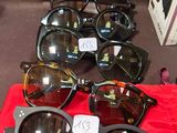 de nombreuses paires de lunettes de soleil posées sur un tissu rouge, sur une table