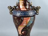 un vase orné d'un hippocampe et posé sur une table