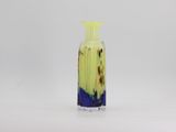 a yellow and blue vase sitting on a white surface