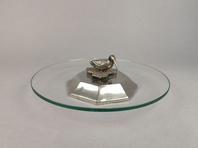 une plaque de verre sur laquelle est posé un oiseau en argent