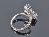 a close up of a diamond and sapphire ring on a reflective surface