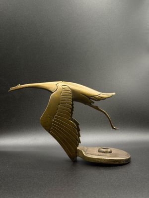sculpture of a bird flying over a coin on a gray surface