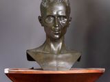 a bronze bust of a man on a wooden shelf