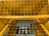 a yellow crate with a metal cage on top of it