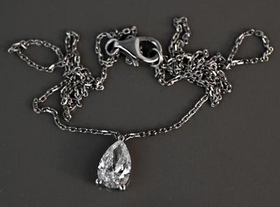 a silver necklace with a tear shaped diamond hanging from it