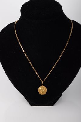 un collier avec une pièce d'or sur un mannequin noir
