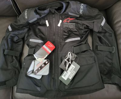a black jacket with tags on it sitting on a couch