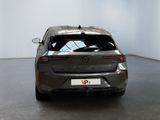 the rear end of a grey car in a room with a white wall