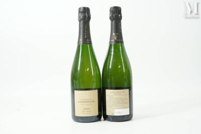 deux bouteilles de champagne posées l'une à côté de l'autre sur une surface blanche