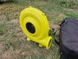 a yellow blower sitting on the ground next to a black bag