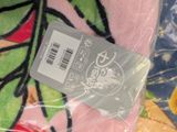 a pink blanket with a label on it on a bed