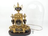 a clock that is under a glass dome on a table