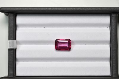 une tourmaline rose dans un écrin noir posé sur un fond blanc