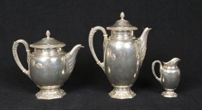 three silver teapots and a sugar bowl on a black background