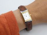 a woman wearing a watch on her wrist with a brown leather band