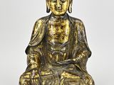 a gold statue of a buddha sitting on a white surface