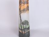 a tall vase with a painting of trees on it