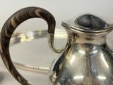 a silver tea pot with a wooden handle on a table