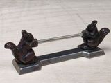 two small figurines of squirrels on a metal stand