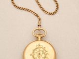 a close up of a gold pocket watch on a chain