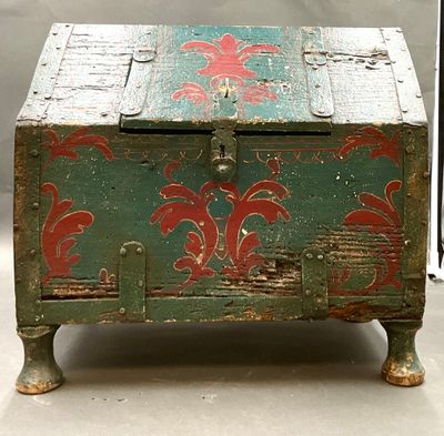 un coffre vert orné de motifs rouges, posé sur une table