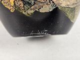 a black vase with gold and green designs on it