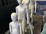Plusieurs mannequins sont alignés dans une pièce où se trouve une chaise bleue