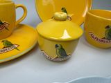 a yellow cup and saucer with a green parrot on it