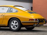 yellow porsche 911 carrol parked in front of a building on a cobblestone street