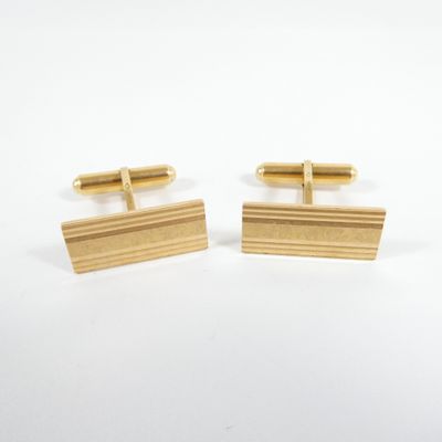a pair of gold cufflinks on a white background