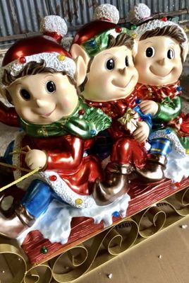 three figurines of elves sitting on a sleigh