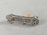 an image of a silver broochle with the word ' bebe ' written on it