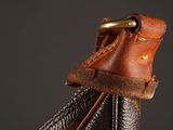 brown and black leather purse with a gold buckle on a black background