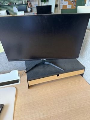 La télévision à écran plat est posée sur le bureau, à côté d'une télécommande.