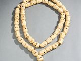 un gros plan d'un collier de perles en bois posé sur une surface grise