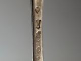 an old silver spoon with writing on it sitting on top of a table