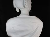 white marble bust of a woman with braided hair on a black background