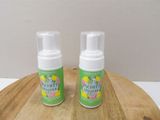 two bottles of white foam sitting on top of a wooden cutting board