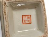 a small square bowl with a chinese writing on it