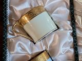 three coffee cups in a box with gold trims on a table