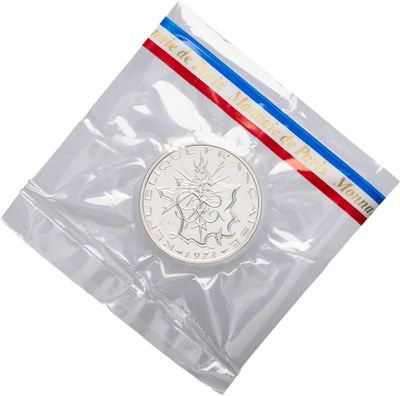 a close up of a coin in a plastic bag on a white background