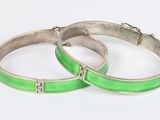 a pair of green enamel bangles with silver clasps