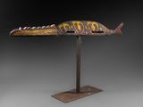 une sculpture en bois représentant un poisson, posée sur un socle en métal